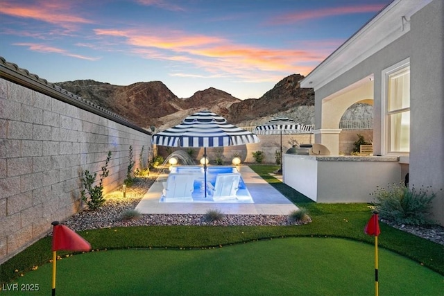 38 Costa Tropical Dr, Henderson, NV 89011 - yard at dusk featuring a putting area, a patio area, a fenced backyard, and a mountain view