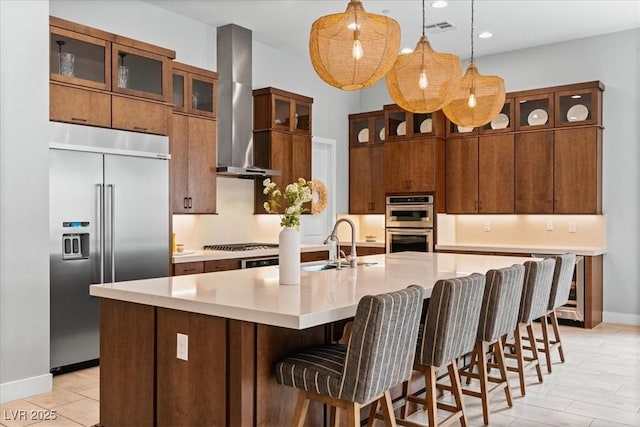 38 Costa Tropical Dr, Henderson, NV 89011 - kitchen with stainless steel appliances, wall chimney exhaust hood, light countertops, hanging light fixtures, and baseboards