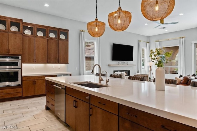38 Costa Tropical Dr, Henderson, NV 89011 - kitchen featuring a sink, open floor plan, appliances with stainless steel finishes, light countertops, and a warm lit fireplace