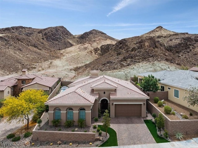 38 Costa Tropical Dr, Henderson, NV 89011 - view of front of house with a garage, stucco siding, driveway, a chimney, and a mountain view