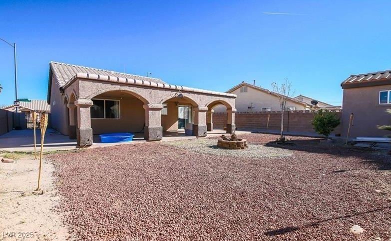 back of house featuring a tile roof, a patio, a fenced backyard, and stucco siding