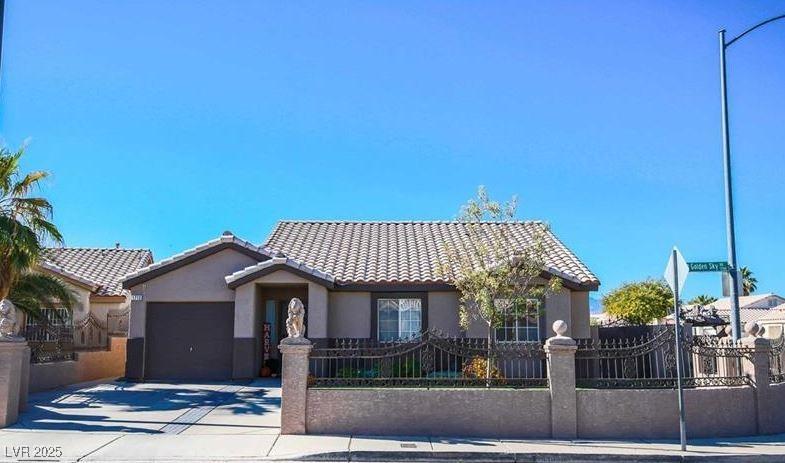 single story home with an attached garage, driveway, a tile roof, a fenced front yard, and stucco siding
