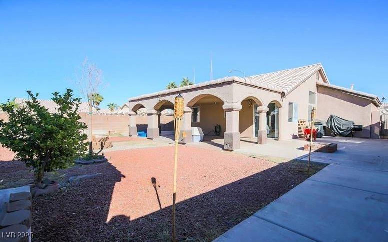 rear view of property with a patio, stucco siding, fence, and a tile roof