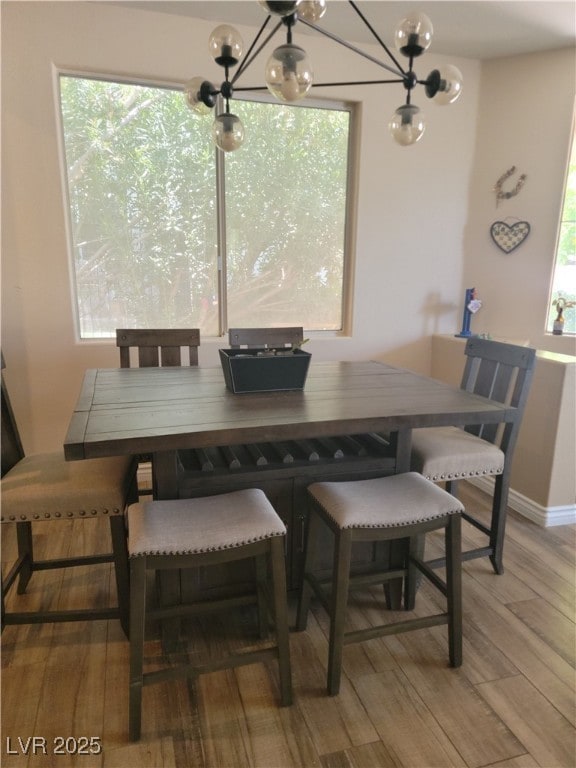 dining space with a chandelier, light wood finished floors, and baseboards