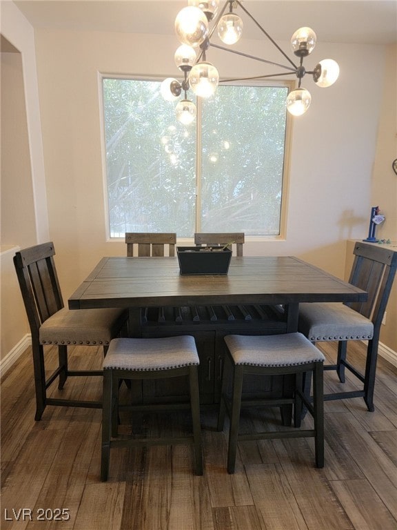 dining space featuring wood finished floors, baseboards, and a chandelier