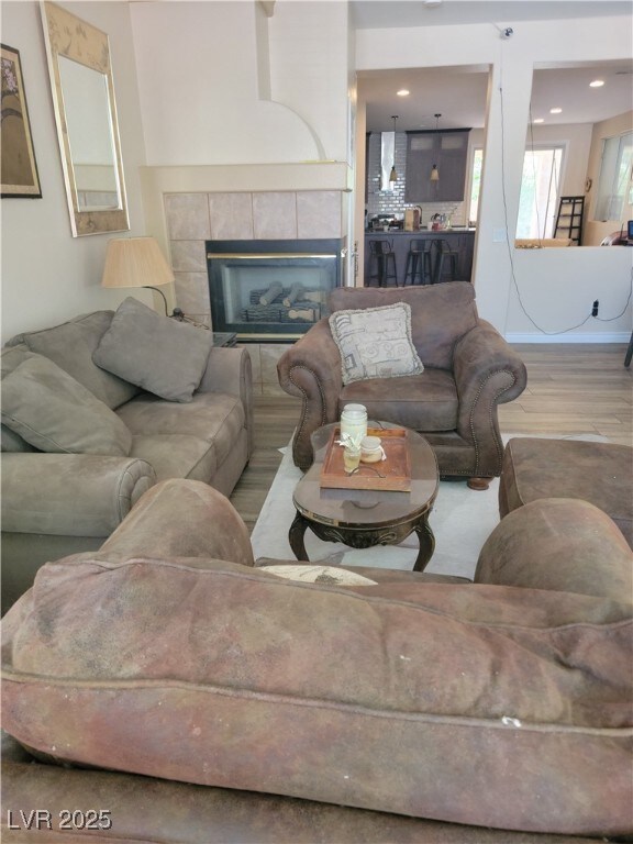 living area with wood finished floors and a tile fireplace