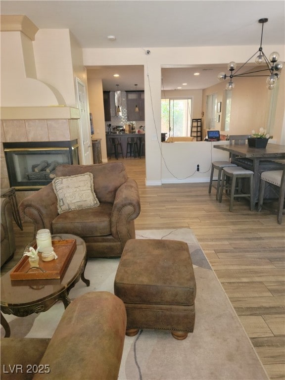 living area with light wood finished floors, a tiled fireplace, and recessed lighting