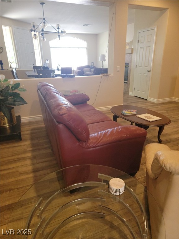living room featuring wood finished floors, baseboards, and a chandelier