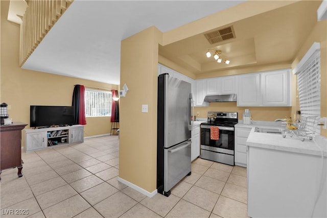 4770 Topaz St Unit 108, Las Vegas, NV 89121 - kitchen featuring stainless steel appliances, light tile patterned floors, under cabinet range hood, a tray ceiling, and white cabinetry