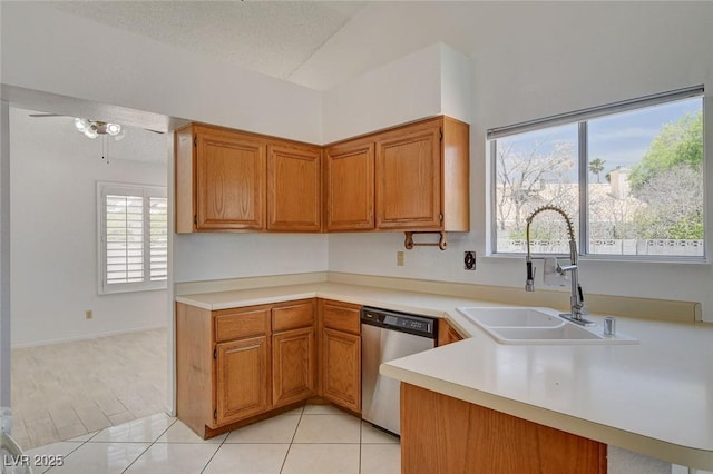 6432 Jean Lee Dr, Las Vegas, NV 89108 - kitchen with stainless steel dishwasher, a sink, light countertops, brown cabinets, and a ceiling fan