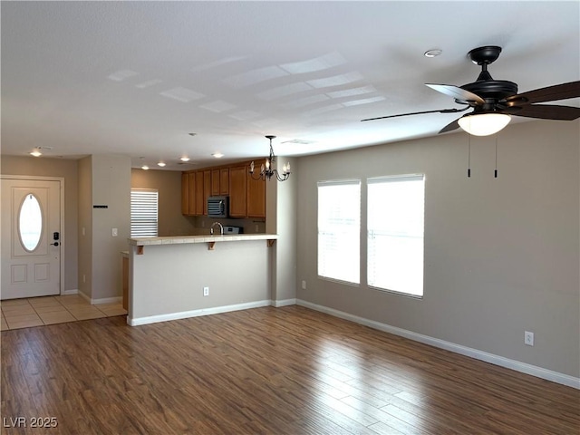 unfurnished living room with a chandelier, light wood-style flooring, baseboards, a ceiling fan, and recessed lighting
