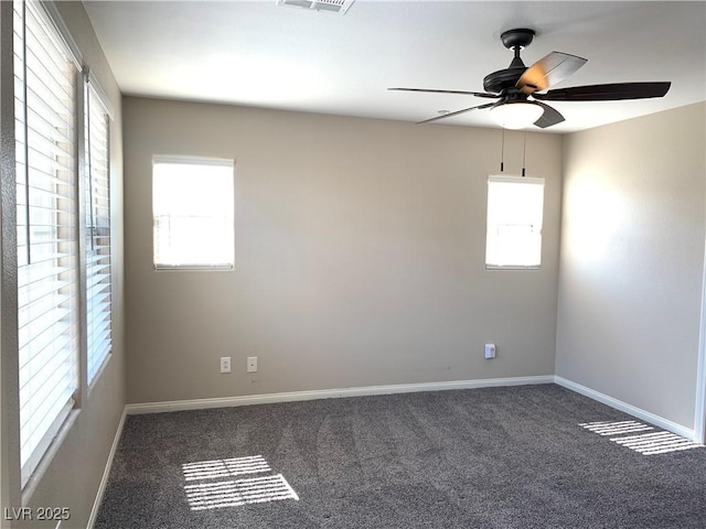 carpeted spare room with healthy amount of natural light, a ceiling fan, and baseboards