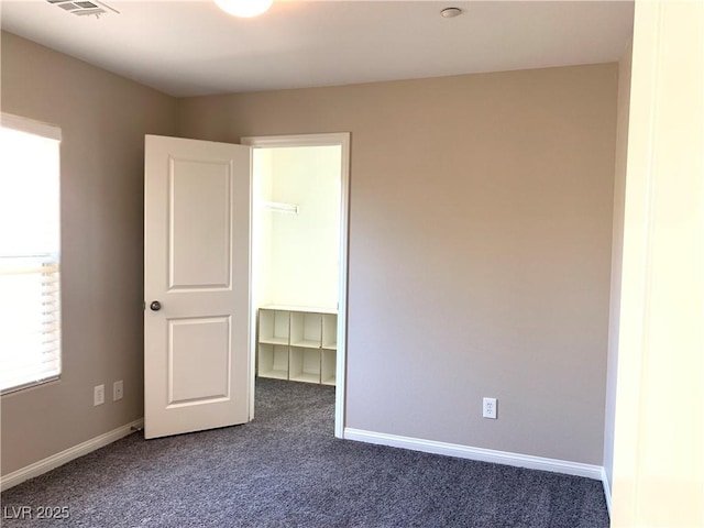 unfurnished room featuring dark colored carpet and baseboards