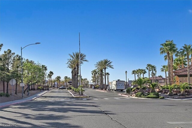 view of asphalt road with curbs, traffic signs, sidewalks, and street lights