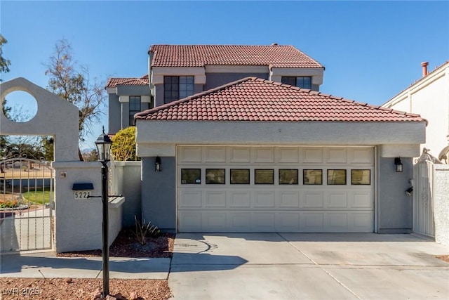mediterranean / spanish house featuring a tiled roof, stucco siding, and a gate