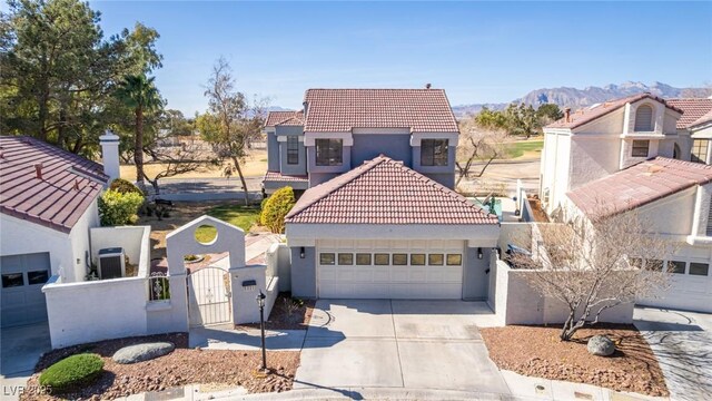 mediterranean / spanish-style house featuring a tile roof, a gate, stucco siding, a mountain view, and concrete driveway