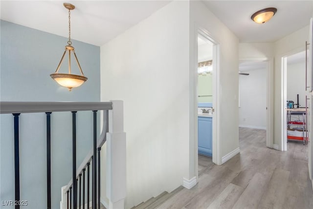 hallway featuring an upstairs landing, light wood-style flooring, and baseboards