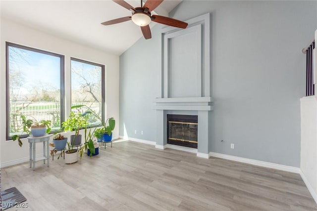living room featuring ceiling fan, a fireplace, lofted ceiling, wood finished floors, and baseboards