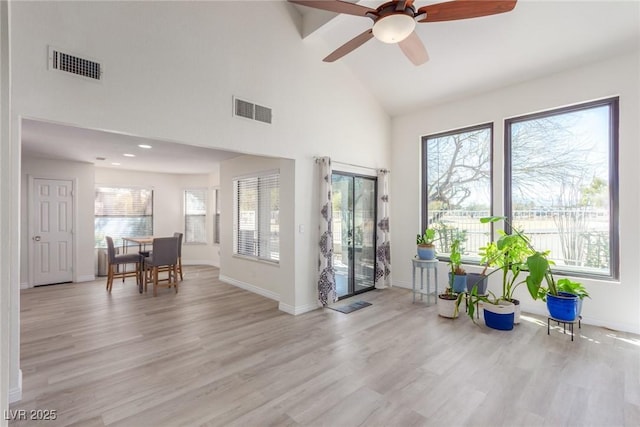 foyer featuring light wood finished floors, ceiling fan, baseboards, and high vaulted ceiling
