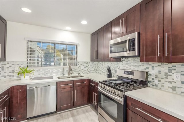 kitchen with stainless steel appliances, a sink, light countertops, light wood-style floors, and tasteful backsplash