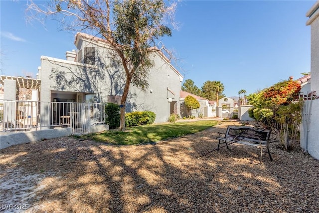 rear view of property featuring stucco siding, fence, and a residential view