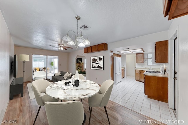 729 Scottsdale St, Henderson, NV 89002 - dining space with ceiling fan, arched walkways, light wood-type flooring, a chandelier, and a textured ceiling