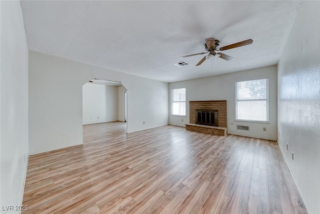 729 Scottsdale St, Henderson, NV 89002 - unfurnished living room featuring a ceiling fan, light wood-style flooring, arched walkways, and a brick fireplace