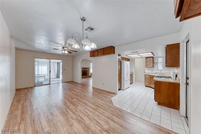 729 Scottsdale St, Henderson, NV 89002 - kitchen with open floor plan, brown cabinetry, freestanding refrigerator, arched walkways, and light countertops