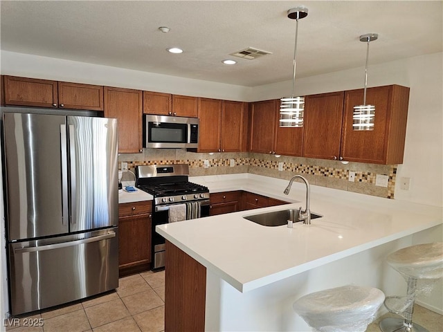 7461 Enviable Ct, Las Vegas, NV 89149 - kitchen featuring stainless steel appliances, a sink, brown cabinetry, a peninsula, and light countertops