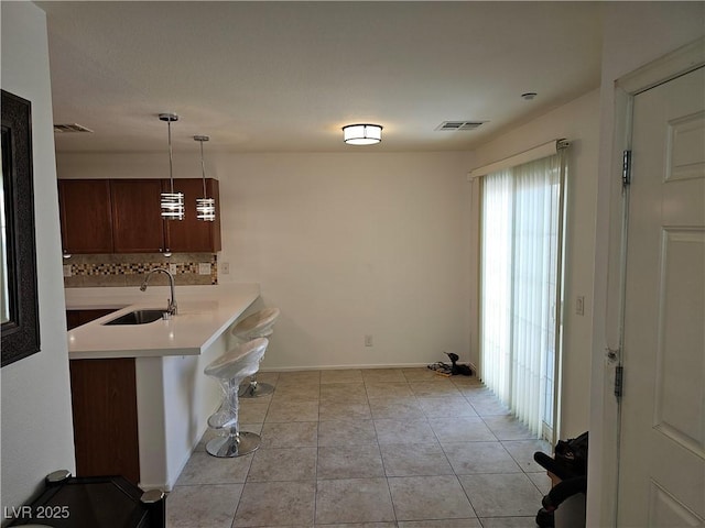 7461 Enviable Ct, Las Vegas, NV 89149 - kitchen with a sink, light countertops, backsplash, light tile patterned floors, and pendant lighting