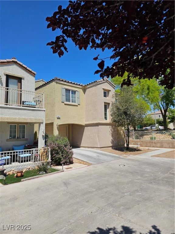 7461 Enviable Ct, Las Vegas, NV 89149 - view of front facade featuring stucco siding, concrete driveway, a tiled roof, a balcony, and fence