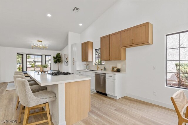 kitchen featuring dishwasher, high vaulted ceiling, light countertops, a chandelier, and a breakfast bar