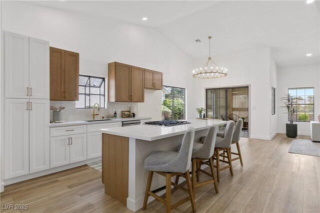 kitchen featuring a sink, light countertops, a kitchen island, light wood-type flooring, and high vaulted ceiling