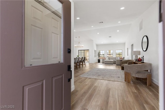 entrance foyer with light wood finished floors, baseboards, and a chandelier