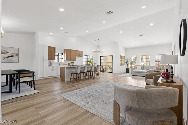 living room with healthy amount of natural light, a chandelier, light wood-style flooring, recessed lighting, and high vaulted ceiling