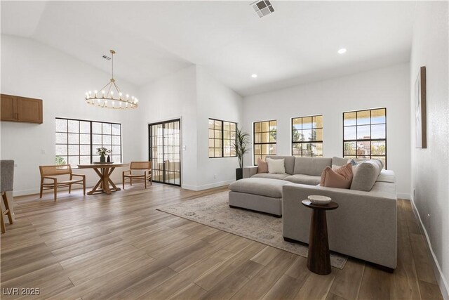 living area featuring baseboards, light wood-style flooring, a chandelier, recessed lighting, and high vaulted ceiling
