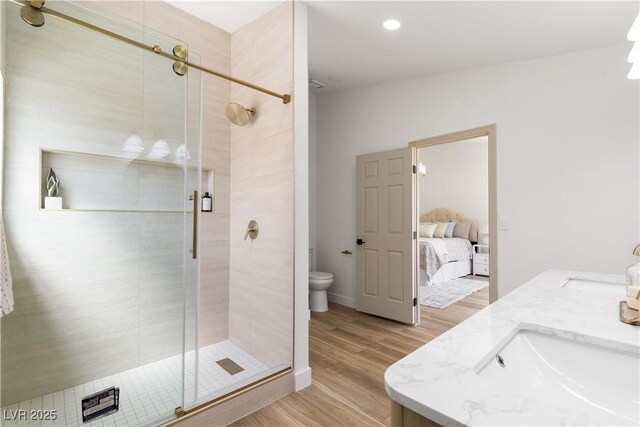 full bathroom with toilet, a stall shower, wood finished floors, ensuite bathroom, and double vanity