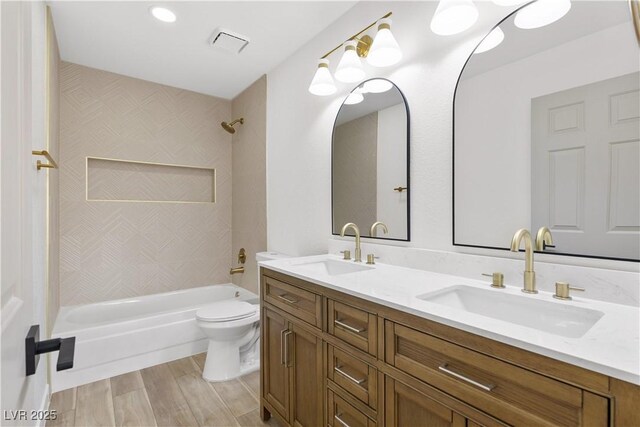 bathroom featuring toilet,  shower combination, wood finished floors, and double vanity