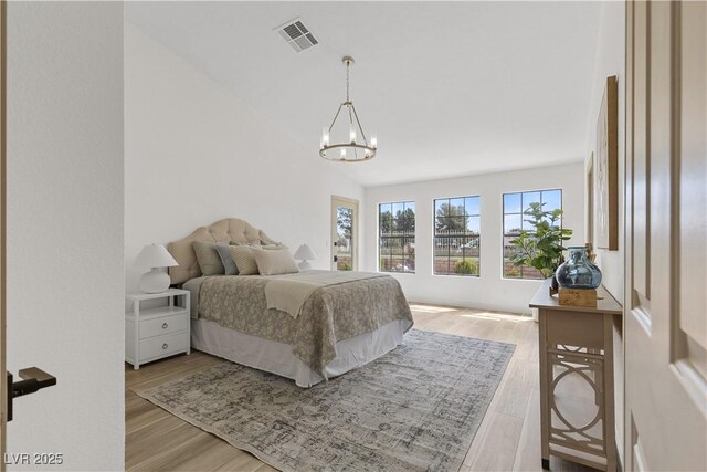 bedroom featuring a chandelier, light wood-style flooring, and vaulted ceiling