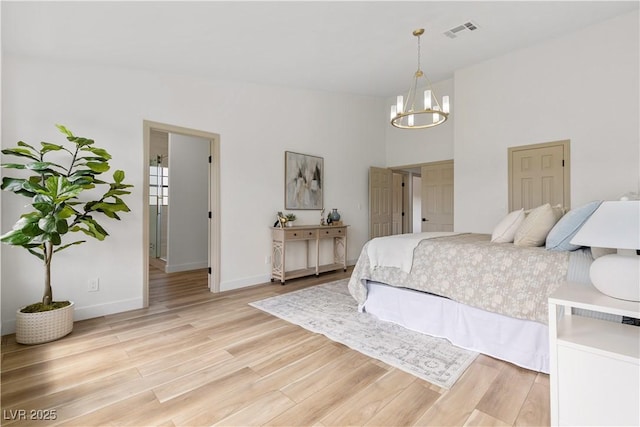 bedroom featuring a chandelier, light wood-style flooring, baseboards, and a high ceiling