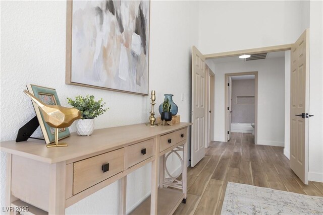 corridor featuring light wood-type flooring and baseboards