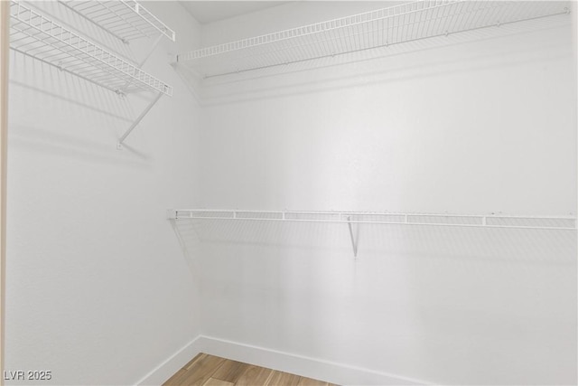 walk in closet with light wood finished floors