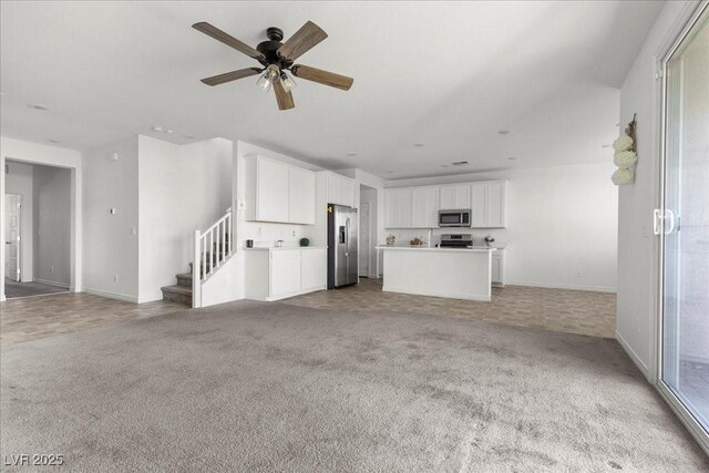 6854 Chargehand Ave, Las Vegas, NV 89156 - unfurnished living room featuring light colored carpet, baseboards, a ceiling fan, and stairway