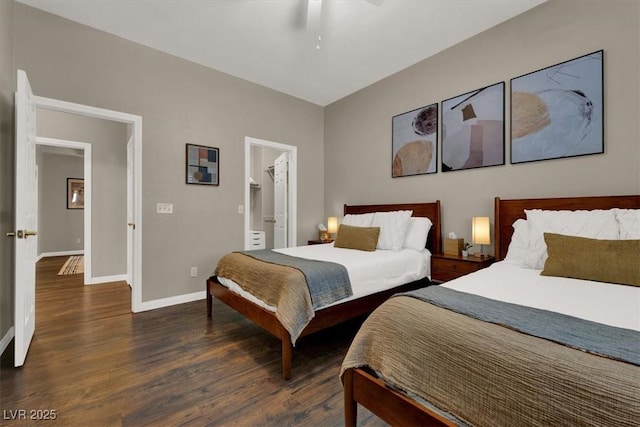 bedroom with wood finished floors, baseboards, a ceiling fan, and a walk in closet