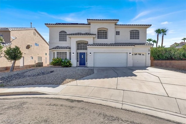 mediterranean / spanish house with a tiled roof, a garage, driveway, and stucco siding