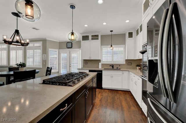 kitchen featuring stainless steel appliances, crown molding, light countertops, tasteful backsplash, and pendant lighting