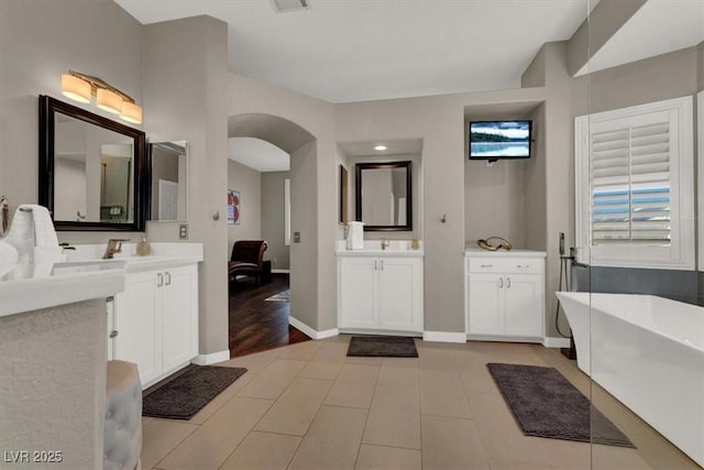 full bath featuring two vanities, a freestanding tub, baseboards, and tile patterned floors