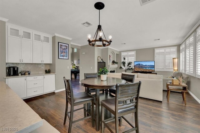 dining space with a chandelier, healthy amount of natural light, dark wood-style flooring, and ornamental molding