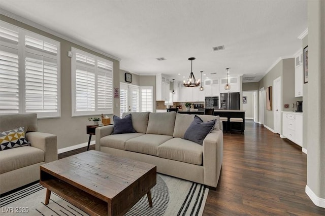 living area featuring a chandelier, ornamental molding, baseboards, and dark wood-style flooring