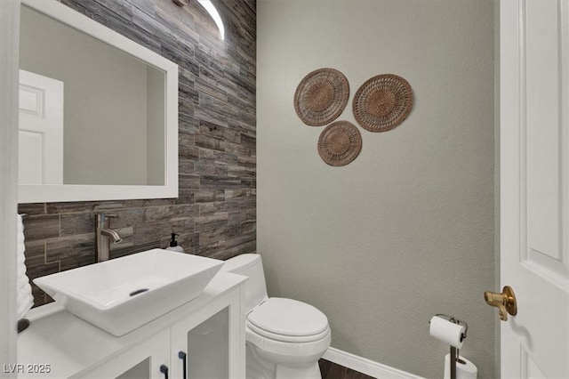 half bathroom with toilet, vanity, and baseboards